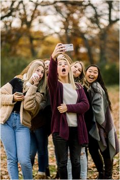 a group of young women standing next to each other taking pictures with their cell phones