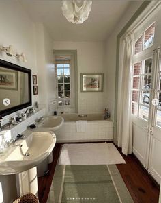 a bathroom with two sinks and a bathtub next to a window in the room