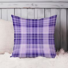 a purple and white plaid pillow sitting on top of a furnishing area next to pillows