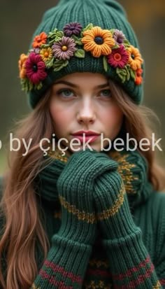 a woman wearing a green hat with flowers on it's head and her hands near her face