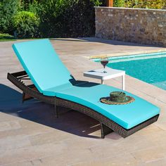 a blue chaise lounge chair sitting next to a swimming pool with a table on it