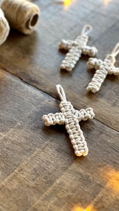 two crocheted crosses sitting on top of a wooden table next to twine