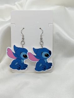 the earrings are shaped like stitchers with blue and pink ears on them, sitting in front of a white background