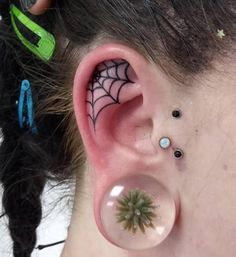 a person with ear piercings on their ears and one has a spider web design