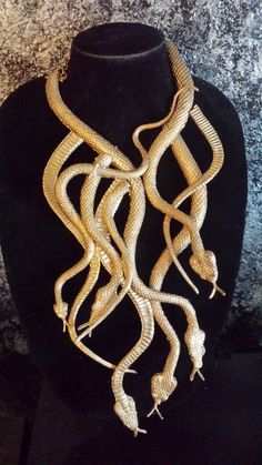 a necklace on a mannequin with gold colored beads hanging from it's neck