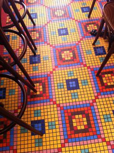 colorful tiles on the floor in a restaurant with chairs and tables next to each other