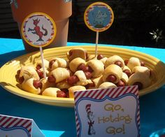 there is a plate full of hotdogs on the table with name tags and place cards