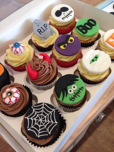 cupcakes decorated to look like halloween characters in a white box on a table