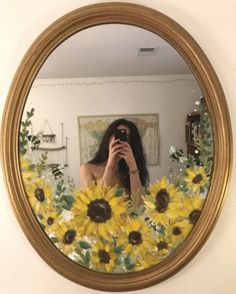 a woman taking a selfie in front of a mirror with sunflowers on it