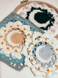 three crocheted flowers are sitting next to each other on a white table top