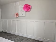 a room with white paneling and pink flowers on the wall, along with gray carpet