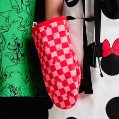 a hand holding a red and white mickey mouse purse on top of a green background