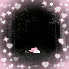 a pink teddy bear laying in the middle of a forest surrounded by heart shaped lights