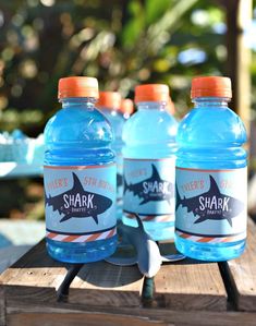 three bottles of shark water sitting on top of a wooden table