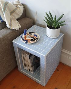 a blue tiled side table with a magazine rack and succulent plant on top