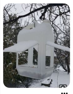 a white lantern hanging from a tree covered in snow