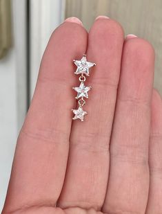 someone is holding out their hand with three star earrings on it's left side