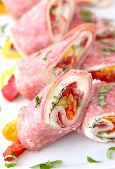 ham and vegetables rolled up on a white plate with green garnish around the edges