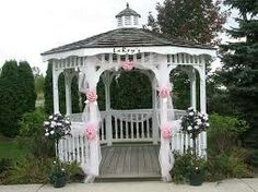 a white gazebo decorated with pink flowers and ribbons