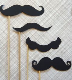 three black mustaches on sticks are sitting next to each other