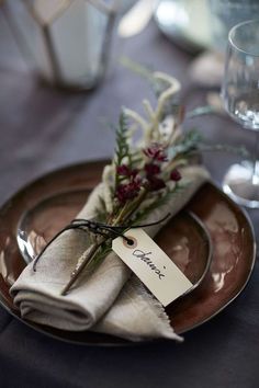 a place setting with napkins and flowers on the plate, along with wine glasses