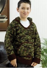 a young boy standing in front of a couch wearing a green and brown knitted sweater