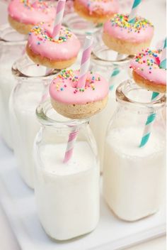 a table topped with glass jars filled with donuts and frosted sprinkles