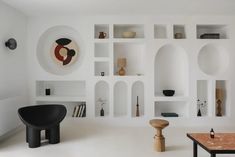 a living room filled with white walls and shelves next to a coffee table on top of a hard wood floor