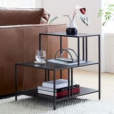 a living room with a couch, coffee table and vase on the end table in front of it