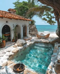 an outdoor swimming pool surrounded by rocks and water features a stone patio with seating area