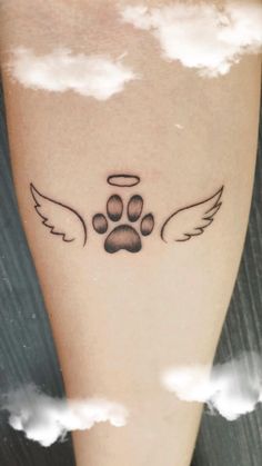 a dog paw with angel wings tattoo on the left calf leg, and clouds in the background