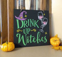 a sign that says drink up witches next to some pumpkins