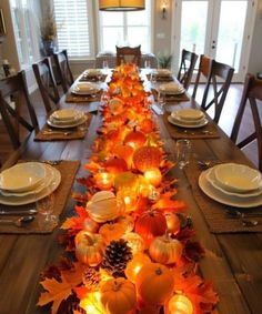 a long table is decorated with candles and pumpkins