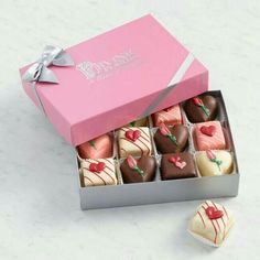 a pink box filled with assorted chocolates on top of a white countertop