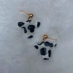 two black and white cow earrings on a white furnishing area with gold ear pins