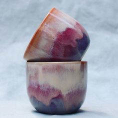 two ceramic bowls sitting side by side on a white surface, one with purple and red designs