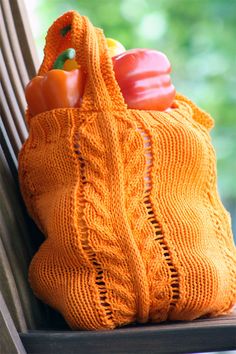 an orange knitted bag sitting on top of a wooden bench next to a window