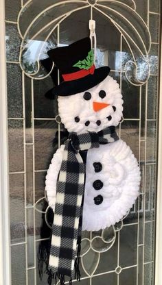 a snowman is hanging on the door with a black and white checkered scarf