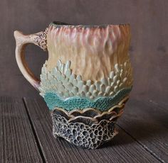 a ceramic mug with an intricate design on the outside and inside is sitting on a wooden surface