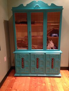 an old china cabinet painted teal with wood floors