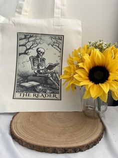 a sunflower in a vase next to a white bag with a skeleton on it