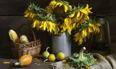 a painting of sunflowers and other flowers in a metal vase on a table