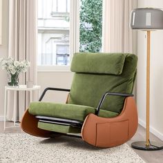 a green recliner chair sitting on top of a rug in front of a window