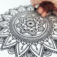 a person is drawing on paper with a pen and inking the design onto it