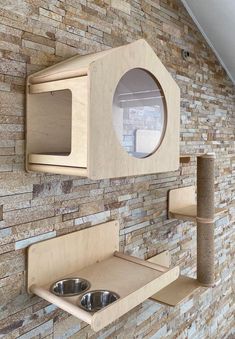 a wooden shelf with two bowls on it and a cat toy in front of the wall