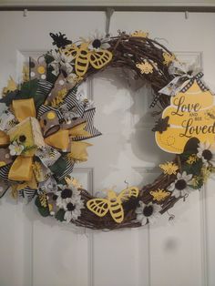 a wreath is hanging on the front door with flowers and bees around it that says love is loved