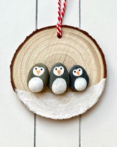 three penguins are sitting on a piece of wood with candy canes in the background