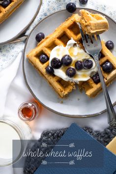 two waffles with blueberries and whipped cream on them, next to a glass of milk