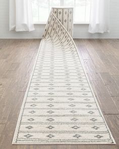 a large white rug on top of a hard wood floor in front of a window