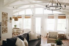 a living room filled with furniture and a chandelier hanging over the top of it